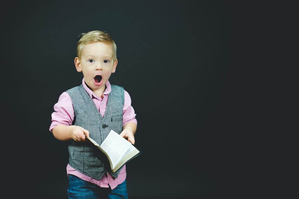 boy wearing gray vest holding book